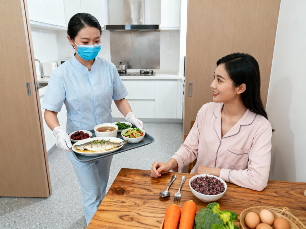 成都家庭厨房场景，月嫂佩戴口罩手套，端着营养搭配的月子餐走向产妇，产妇坐在餐桌旁.png